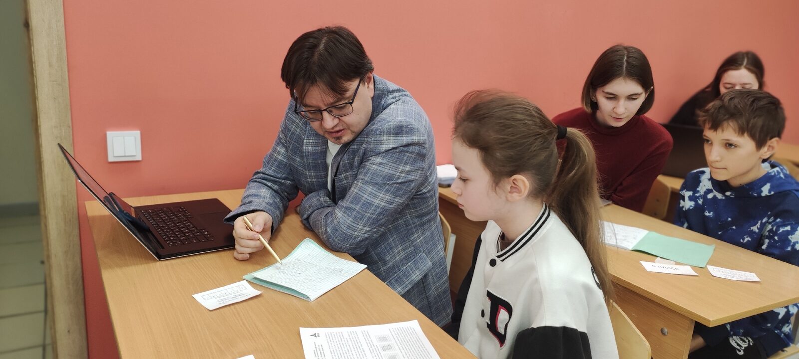 Преподаватель помогает ученику на сборах по подготовке к школьному этапу олимпиады